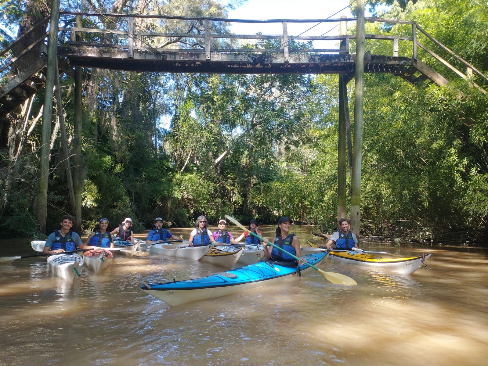 Grupo remando en kayak bajo un puente del Delta de Tigre